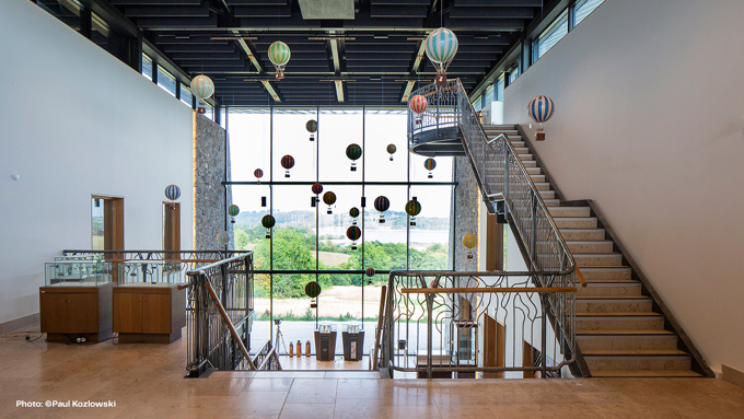 Modern interior of a building featuring a spiral staircase, glass walls, and colorful suspended hot air balloon decorations.
