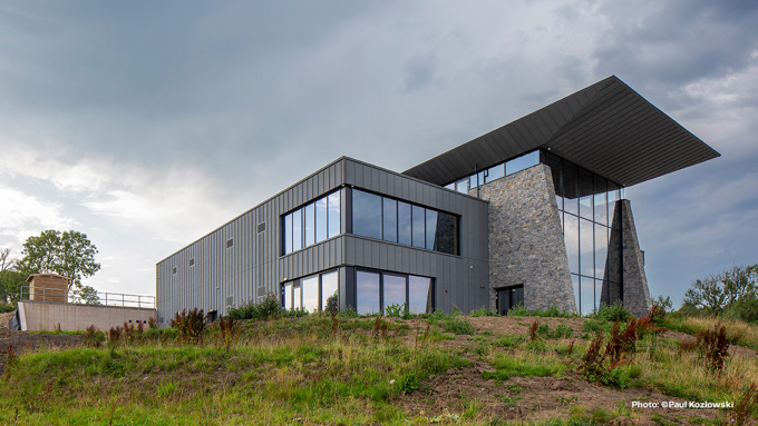 Modern building with gray metal siding and stone accents under a cloudy sky.