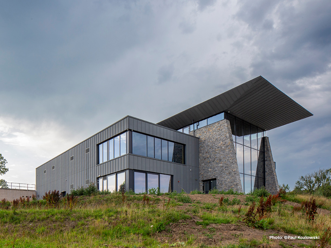 Modern building with gray metal siding and stone accents under a cloudy sky.